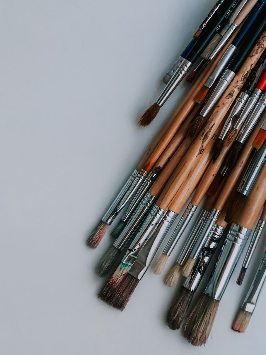 Set of various brushes placed on white desk in art studio